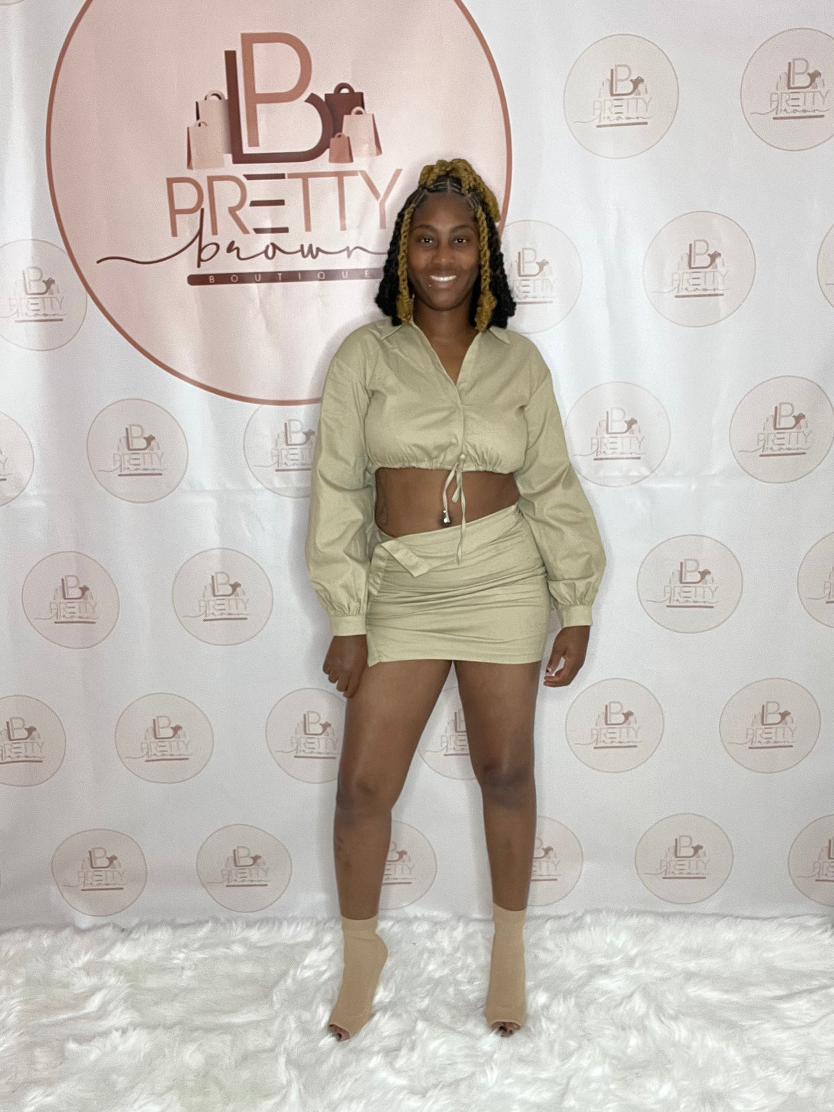 This set includes a long-sleeve crop jacket and a matching mini skirt in a sleek khaki color. 